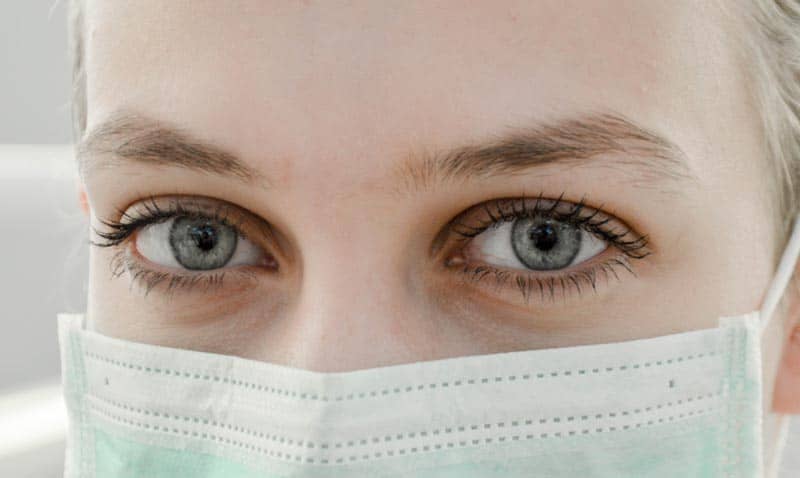 Masked doctor or other healthcare professional looking at camera. CDI is important to improve patient care.