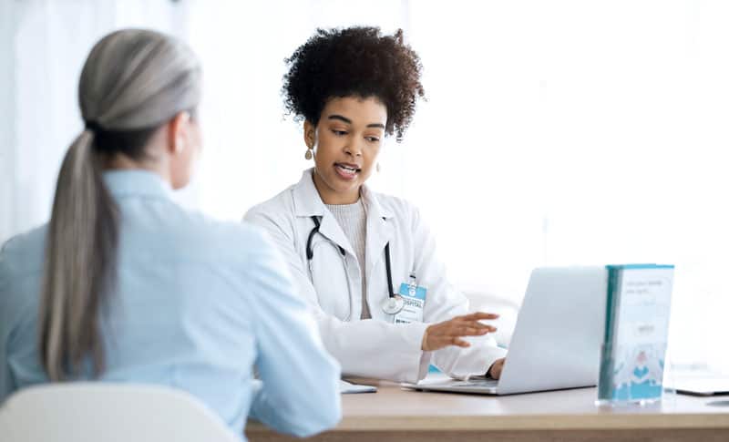 Doctor distracted from eye contact with patient by EMR updating. Hybrid dictation systems give doctors best of both EMR worlds.